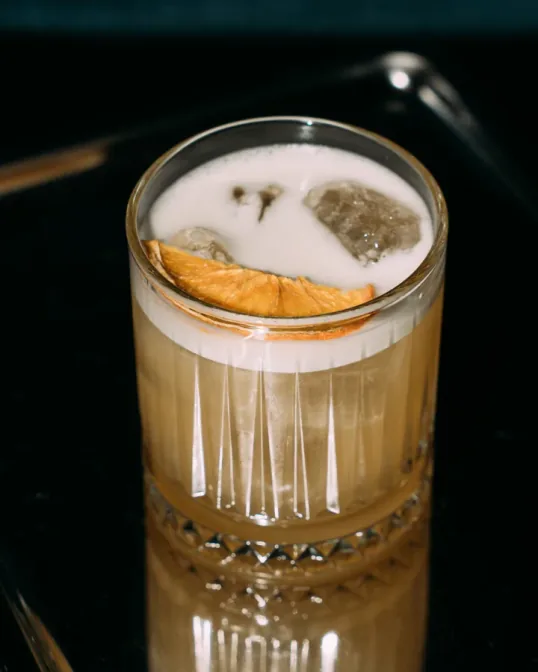 Yuzu Spritz, heller Spritz mit getrockneter Zitrusscheibe in der Adieu Bar Berlin