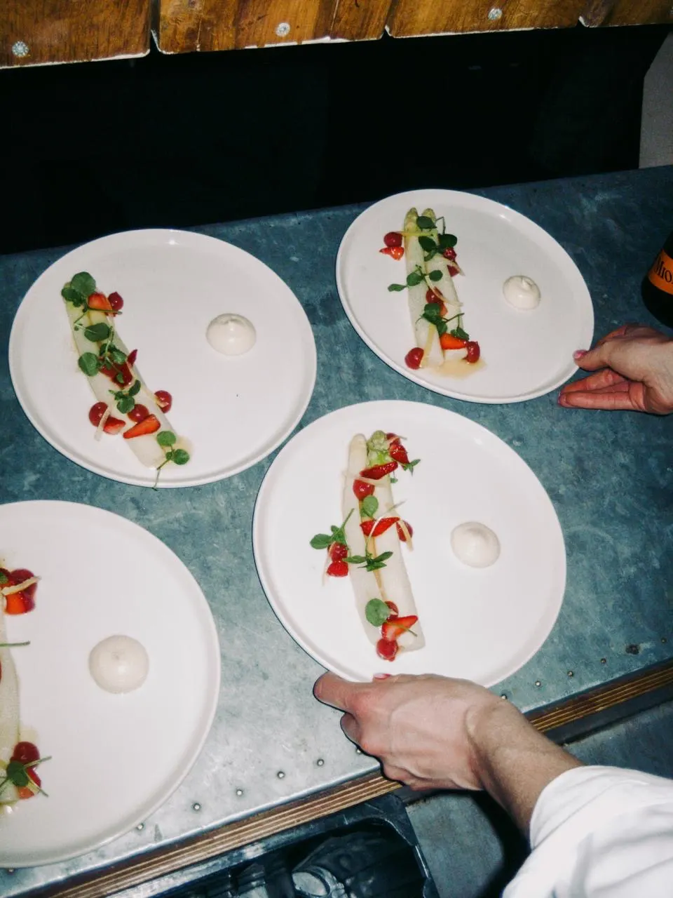 Vier Teller weißer Spargel mit Erdbeeren werden am Pass angerichtet