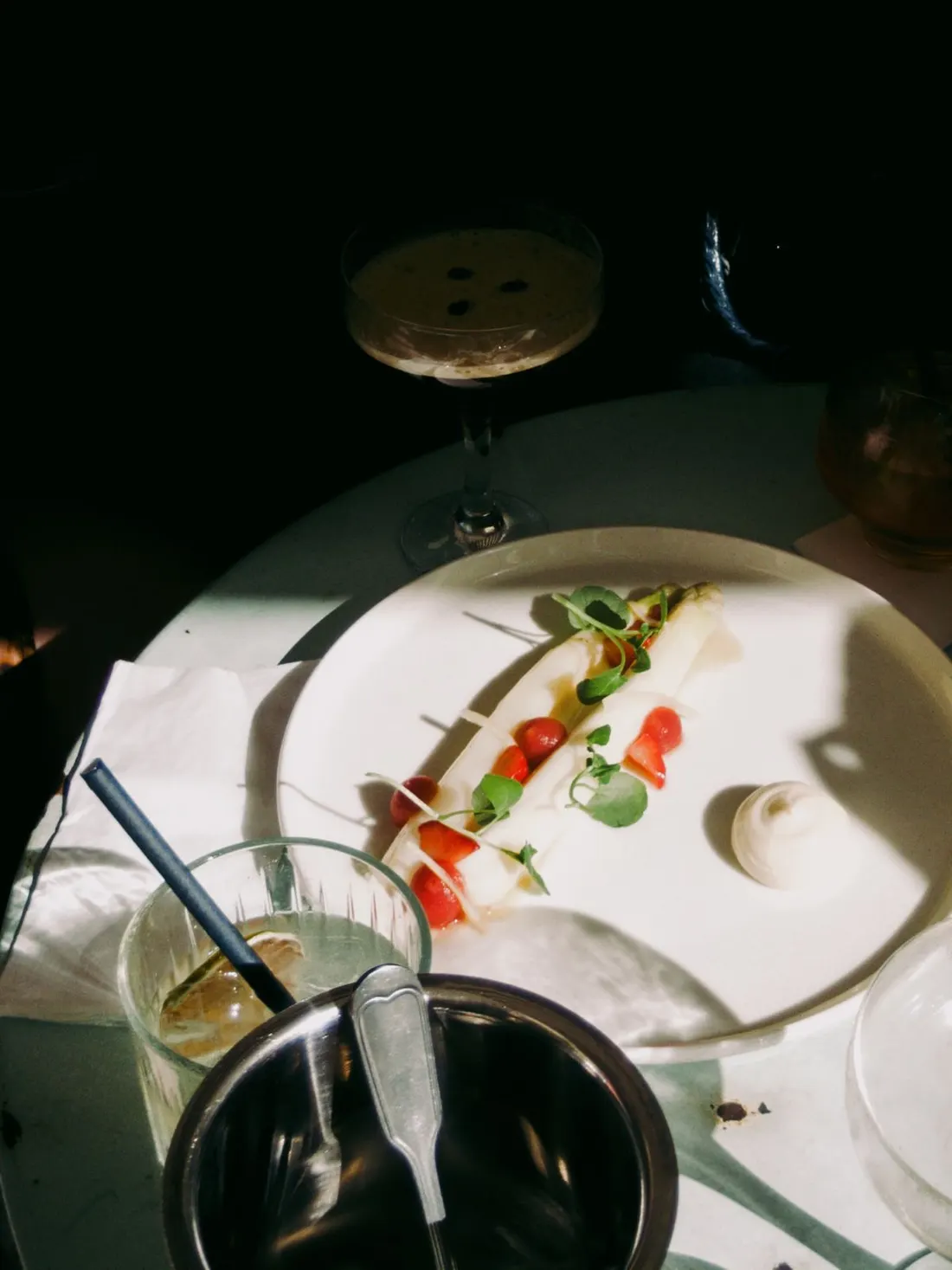Weißer Spargel mit Erdbeeren und einer Nocke Creme auf dem Teller